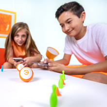 A girl and boy driving their mini through and obstacle course using the included pins and cones. 