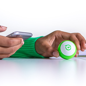 Kid holding iPhone next to Sphero Mini bluetooth connected Sphero Mini toy STEM robot.